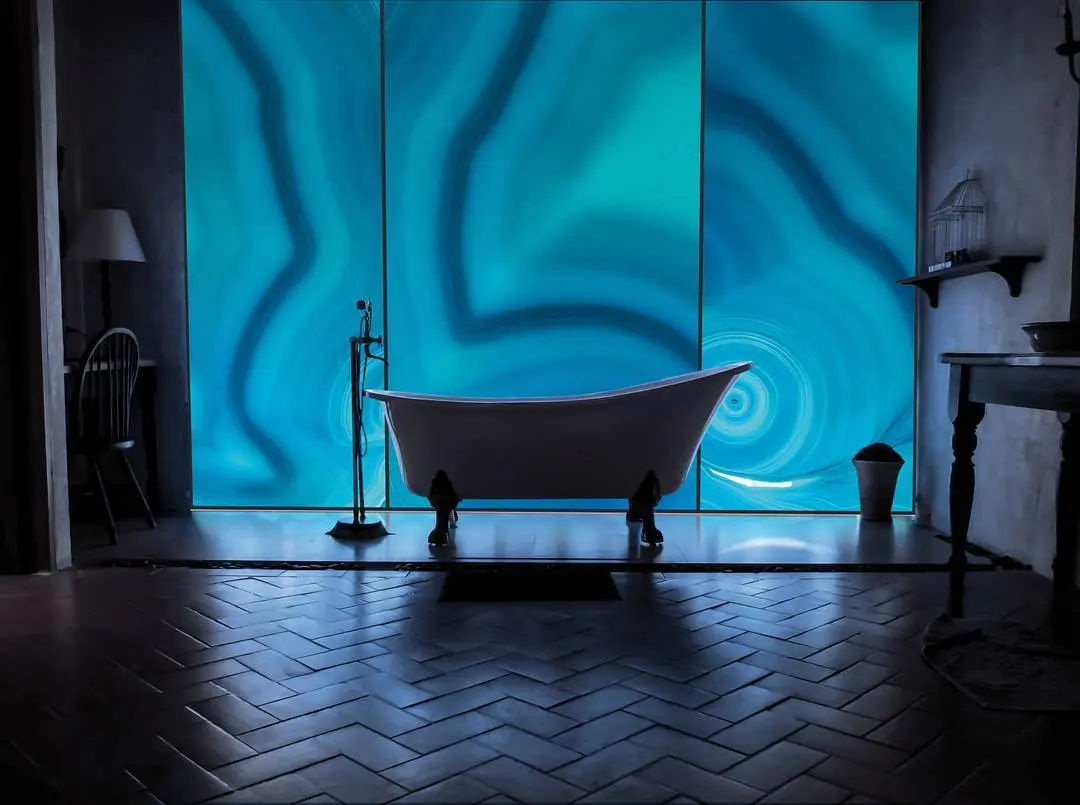 Banheiro com painel azul retroiluminado atrás da banheira