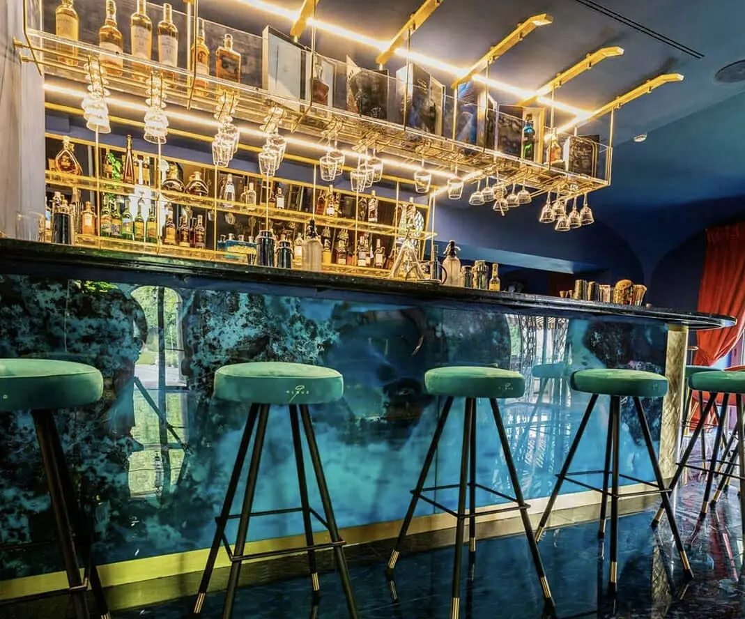 Bar com balcão Pelle retroiluminado em azul e estrutura dourada